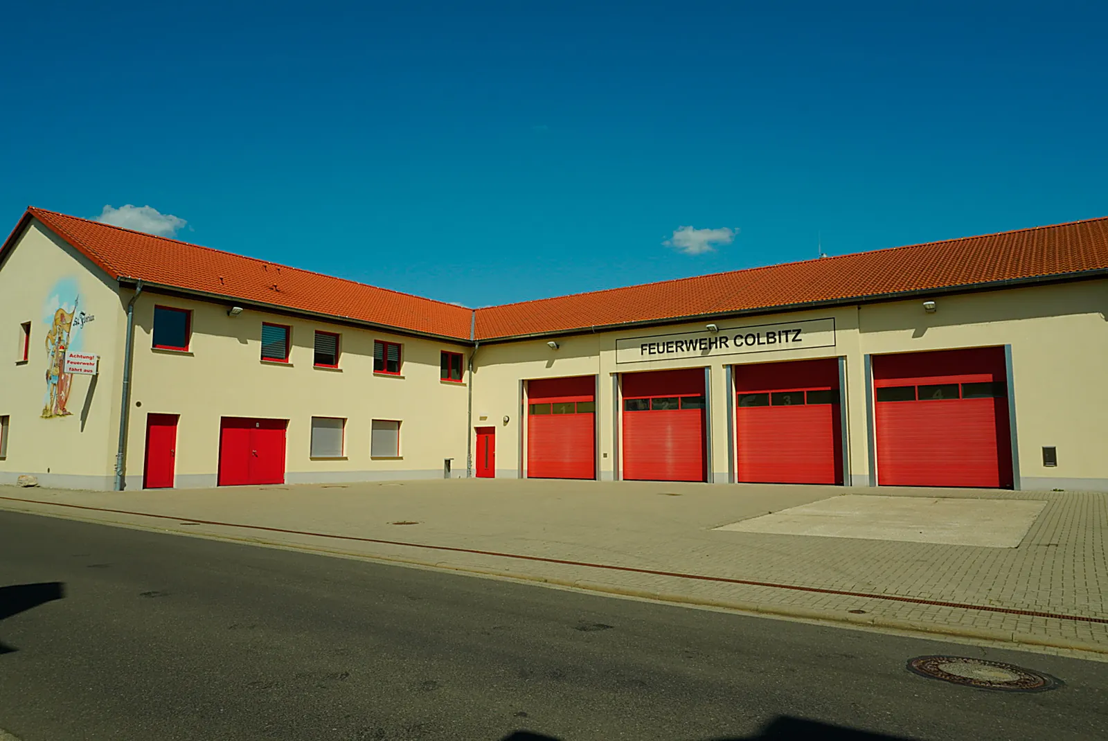 Das Gerätehaus der Feuerwehr Colbitz mit vier roten Toren und dem Florian-Wandgemälde