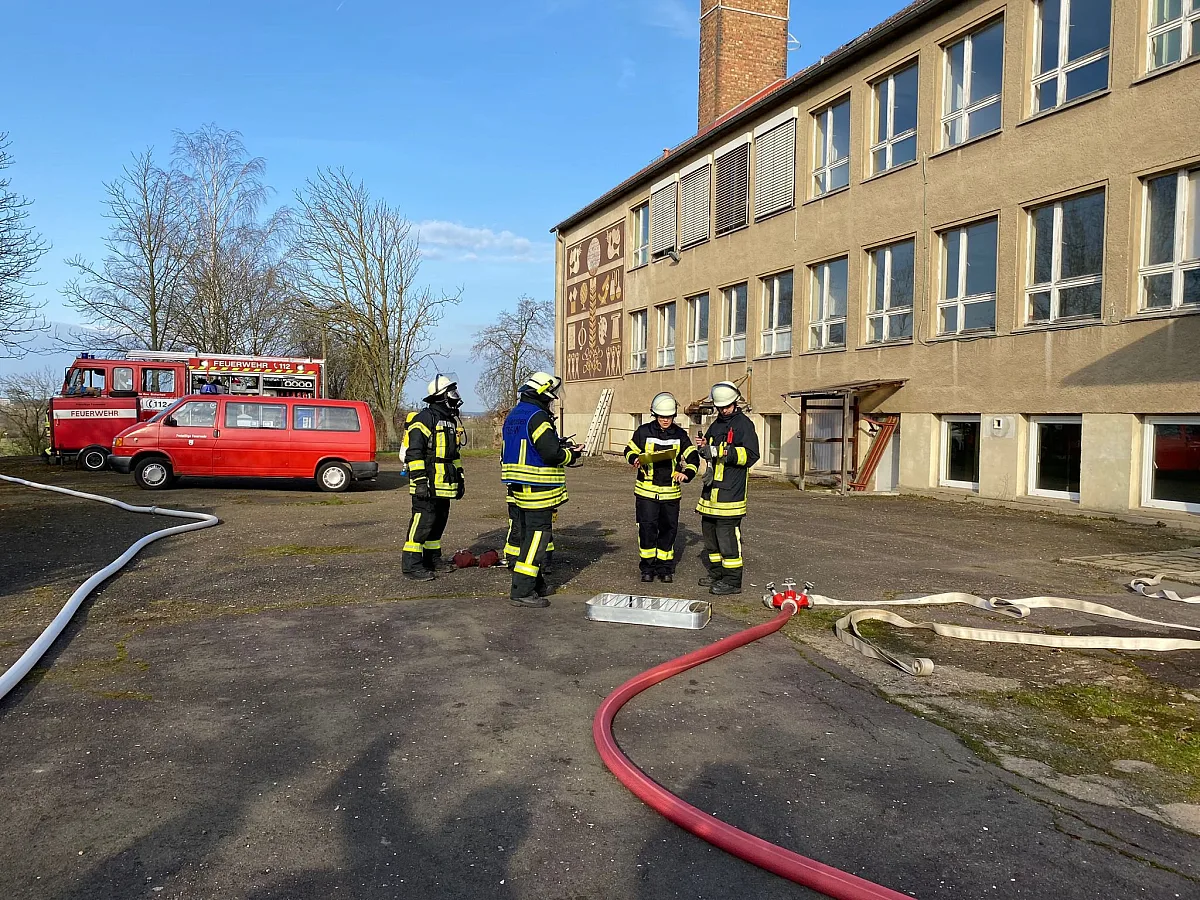 Ein Trupp der Feuerwehr an einer Einsatzstelle mit verlegter Schlauchleitung